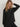 Model wearing the Varley Macie Zip Hem Sweat in Black with one arm raised, showing its relaxed shape and side zip hem.