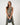Model wearing the TravisMathew Pulse Tank in Olive Smoke with matching leggings while holding a kettlebell.