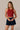 Front view of the J. Pritchard Quiet Lux Tank in Deep Crimson on a model with hands at her waist.