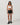 Model wearing Vuori Clementine Retro Shorts in Black with white contrast trim, a white sports bra and black sneakers.”