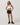 Model wearing Vuori Clementine Retro Shorts in Black with hands on hips, showing their sporty silhouette and contrast trim.