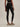 Rear view of Varley Always Contrast High Rise Legging 25 in Black/Snow White, showing the high waistband and fitted cropped legs.