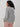 Back view of the Varley Melchie Relaxed Knit Hoodie in Grey Marl, showing its hood, open pointelle stitch and ribbed hem.