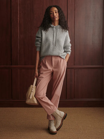 Model wearing the Varley Melchie Relaxed Knit Hoodie in Grey Marl with pink trousers and ankle boots, showing its relaxed fit and pointelle texture.