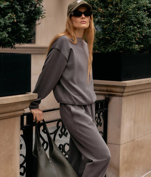 Model wearing the Varley Eli Jogger 27 inch in Anchor outdoors, styled with a matching crew neck sweatshirt.