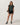 Model wearing the Vuori Energy Classic Tee in Hemlock Heather with black fitted shorts, sneakers and a shoulder bag.