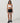 Model wearing Vuori Clementine Retro Shorts in Black with white contrast trim, a white sports bra and black sneakers.”