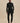 Front view of the black Varley Anset Jacket on a model, showing the high collar, tied waist and longline silhouette.